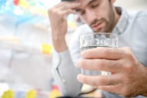 Man with drink in hand looking stressed out