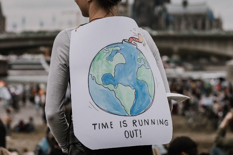 Woman with a sign on her back saying, "Time is running out"