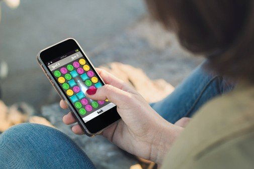 Woman playing CandyCrush-like game on iPhone