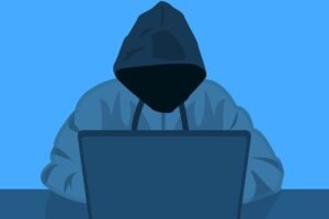hooded figure at laptop