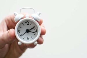 a small white clock held in a man's hand