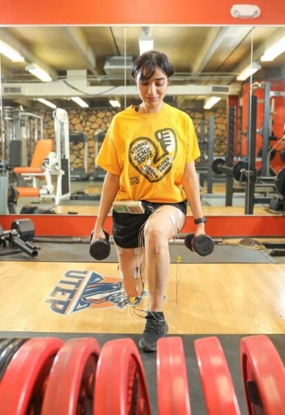 Zahra Fatahimeiabadi, a graduate student in the lab of Sudip Bajpeyi, Ph.D., a professor in the Department of Kinesiology at The University of Texas at El Paso (not pictured), demonstrates a resistance workout while using neuromuscular electrical stimulation (NMES). Bajpeyi leads a team of researchers whose new meta-analysis study, published this month in the European Journal of Applied Physiology, found that combining NMES with resistance training leads to greater muscle mass and strength compared to resistance training alone.