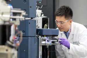 WashU Medicine researcher Kanta Horie, PhD, places a sample in a mass spectrometer that measures protein levels in blood plasma and other fluids. Horie co-led the development of a blood test for Alzheimer’s disease that diagnoses and stages the disease by using mass spectrometry to measure the level of a protein called MTBR-tau243.